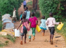 Bambini che corrono con le taniche per l'acqua